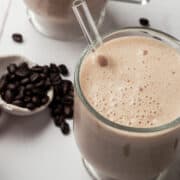 Coffee beans are surrounding the coffee and banana smoothie.