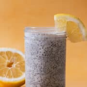 A piece of lemon is on the jar filled with lemon chia seed pudding.