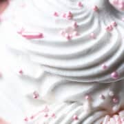 Pink sprinkles are on top of piped whipped cream.