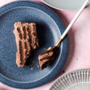 A fork is taking a piece of the chocolate icebox cake from a blue plate.