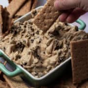 Graham crackers are surrounding the bowl of cookie dough dip.