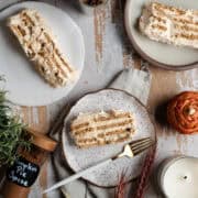 Three slices of pumpkin spice icebox cake are surrounded by Fall things like candles, pumpkin pie spice, and candles.