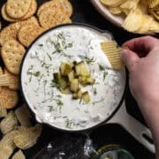 Chopped pickles garnish the top of the dip pickle dip in a skillet.