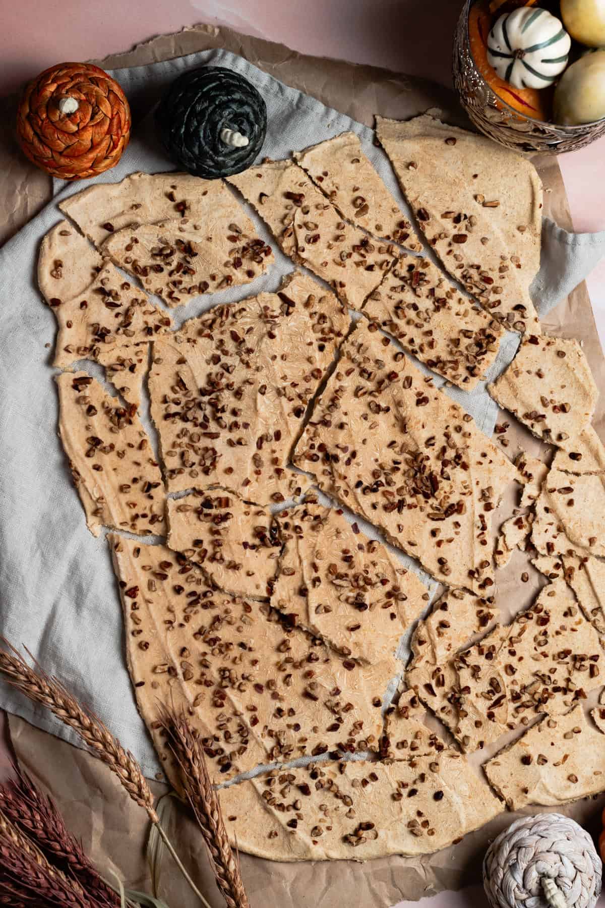 The pumpkin spice yogurt bark is on a piece of parchment paper broken into pieces.