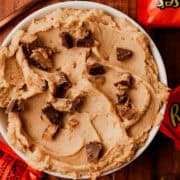The peanut butter cheesecake dip is in a bowl with chopped reeses peanut butter cups.