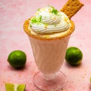 The key lime pie milkshake is topped with whipped cream, grated lime zests, and a graham cracker.
