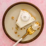 A fork is taking a piece of the no bake lemon cheesecake is on a plate.