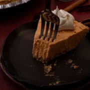 A fork is taking a piece of the no bake pumpkin pie cheesecake off the tip of the pie slice.