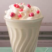 The vanilla milkshake is topped with whipped cream and pink sprinkles.