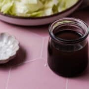 The balsamic vinaigrette is in a small glass container next to the salad.