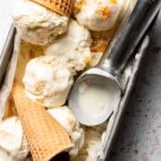 An ice cream scoop is in the loaf pan with with no churn peach ice cream.