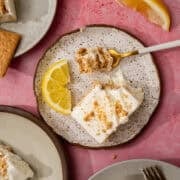 A slice of lemon is on the plate with a slice of the lemon icebox cake.