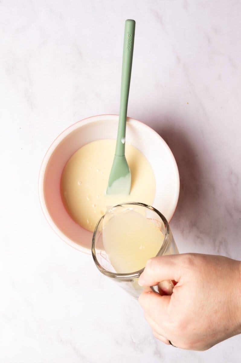 The sweetened condensed milk is in a bowl and the lemon juice is added to the bowl.