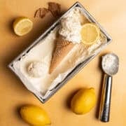 Two full lemons are next to the lemon loaf pan and has an ice cream scoop next to it.