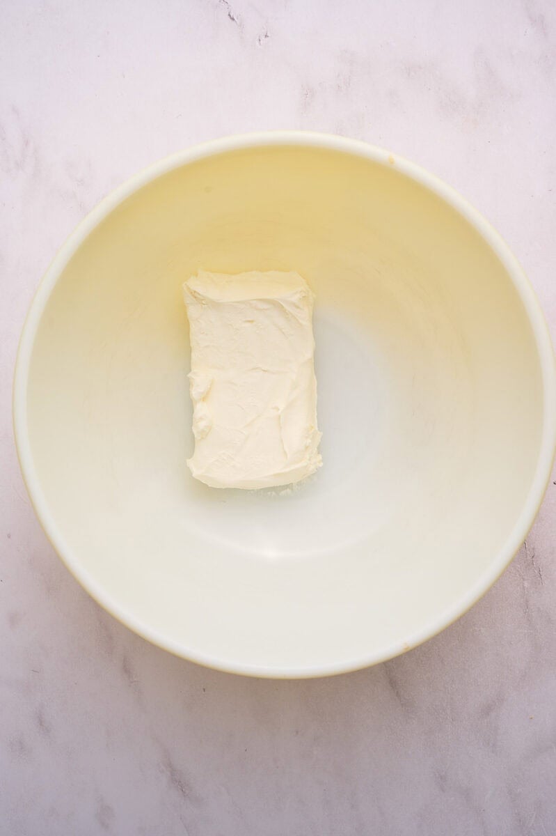 The brick of cream cheese is in a large bowl.