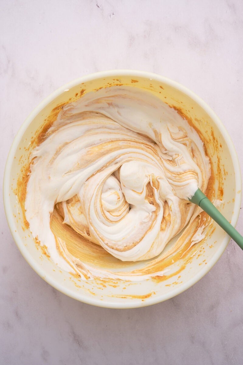 The whipped cream or cool whip is added to the bowl.