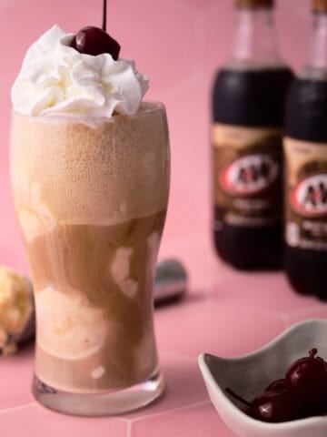The root beer float is in a large glass with two root beers behind them.