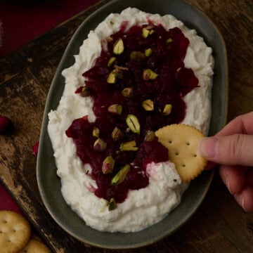 A ritz cracker is dipping into the feta cranberry dip.