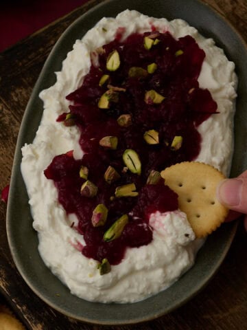 A ritz cracker is dipping into the feta cranberry dip.
