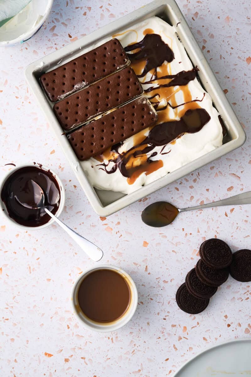 Another layer of ice cream sandwiches are on top of the fudge and whipped topping.