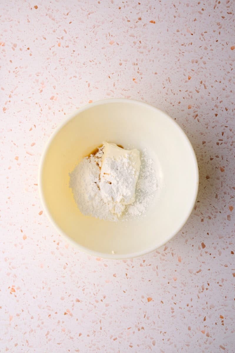 The cream cheese, vanilla extract, and powdered sugar are in a large bowl.