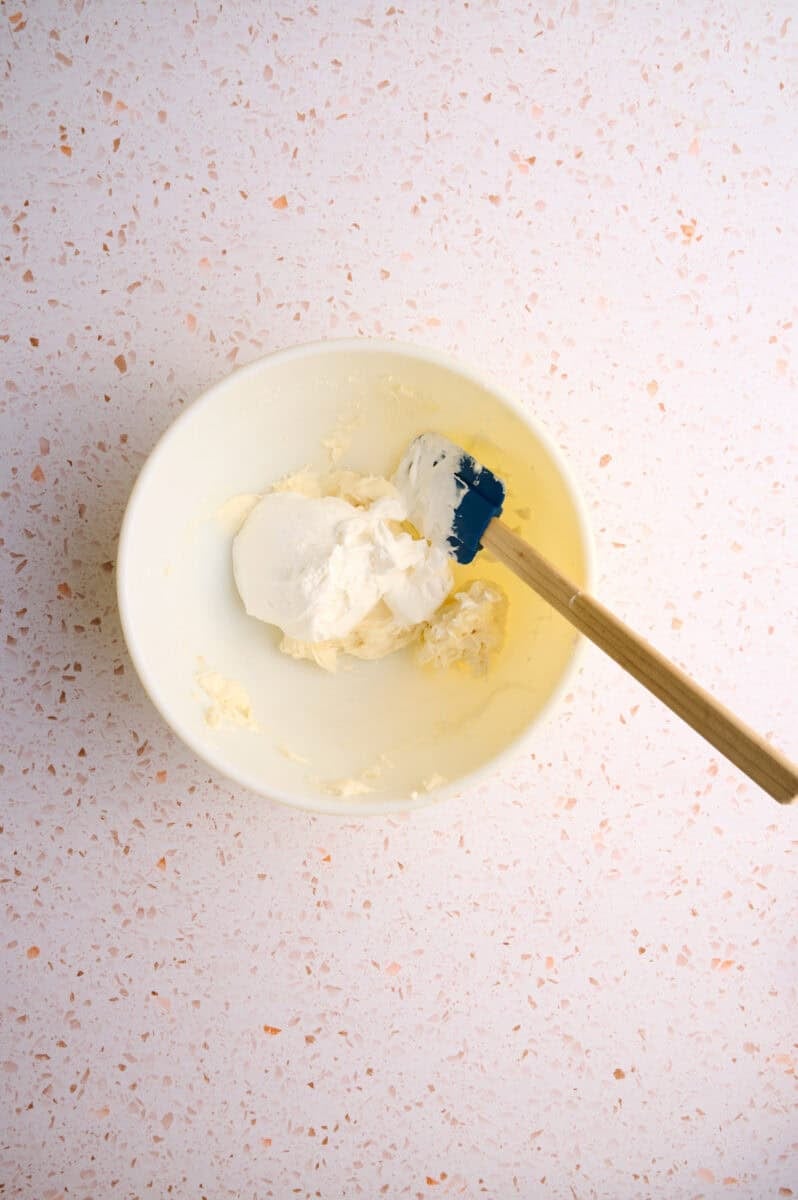 The cool whip is added to the bowl.