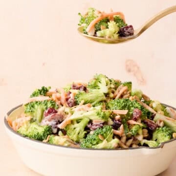 A spoon is taking some of the broccoli crunch salad out of the bowl.