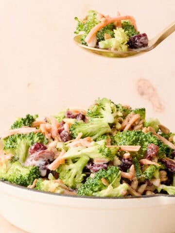 A spoon is taking some of the broccoli crunch salad out of the bowl.