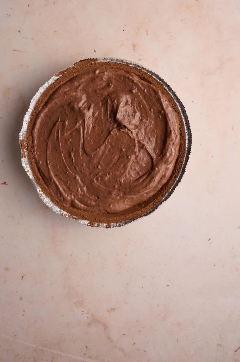 The no bake chocolate pie filling is added to a pie crust.