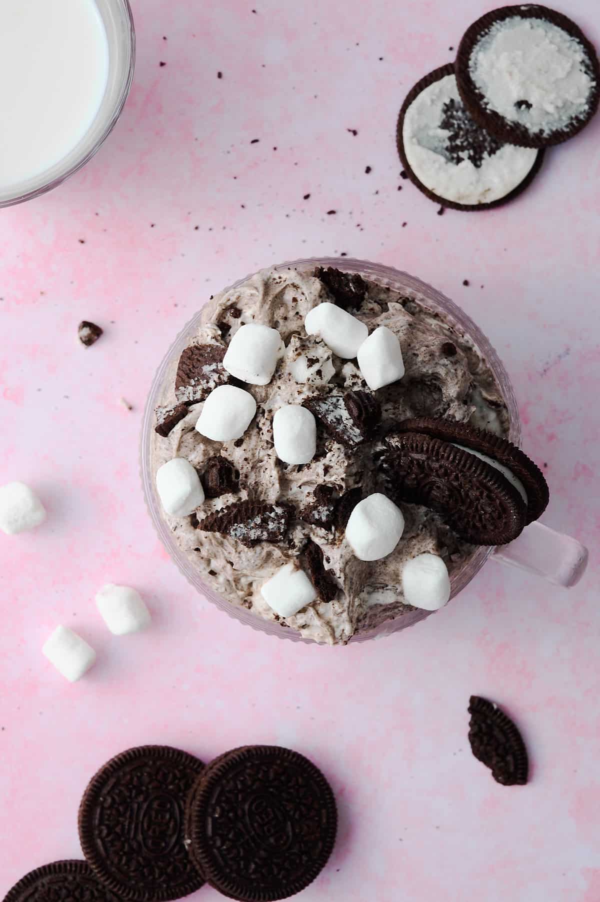 The marshmallows and Oreos are surrounding the Oreo fluff in a glass mug.