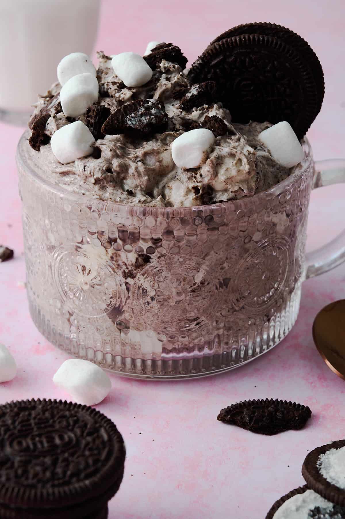 The Oreo fluff are in a large glass mug topped with Oreos and mini marshmallow fluffs.