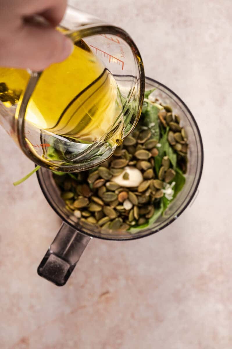 The olive oil is added to the pepita pesto. 