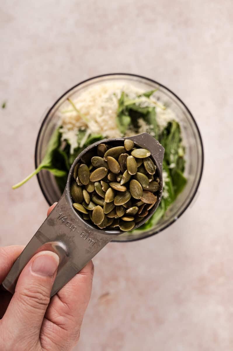 The pumpkin seeds are added to the food processor. 