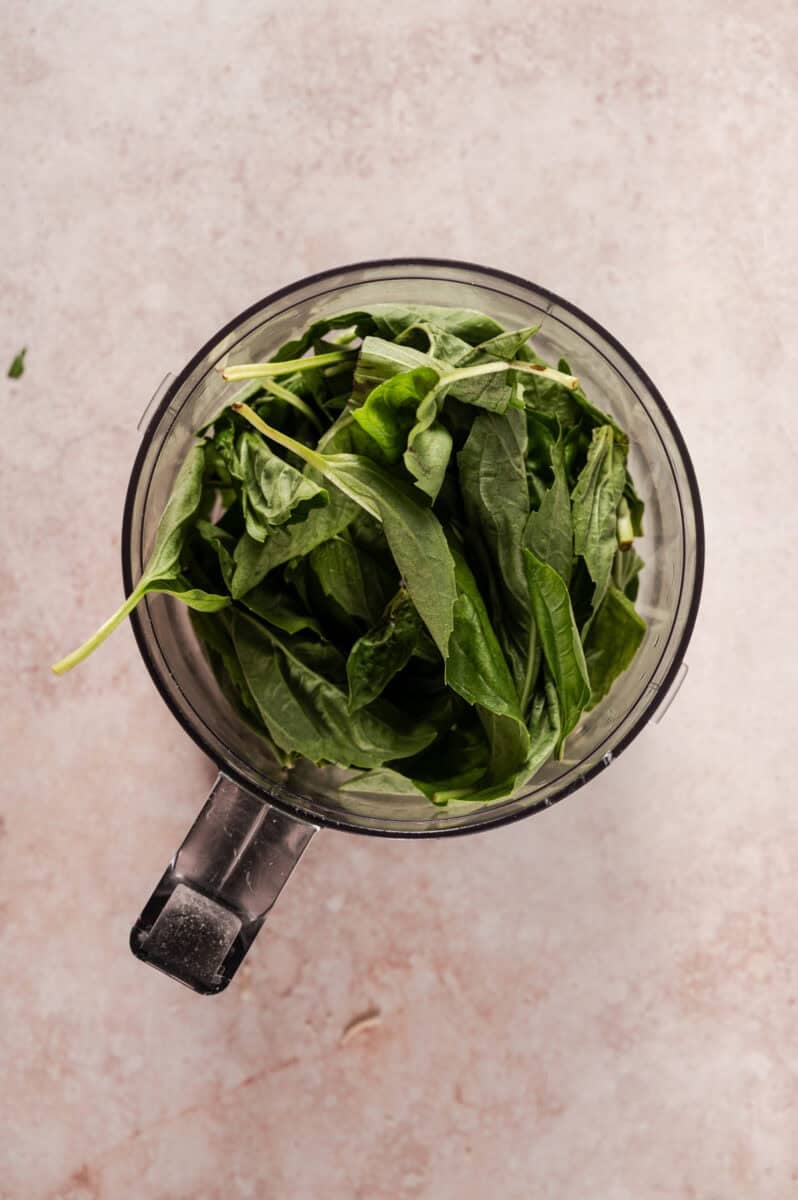 The basil is packed into the food processor. 